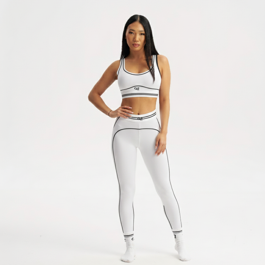 Woman wearing a white sports bra and leggings set on a white background