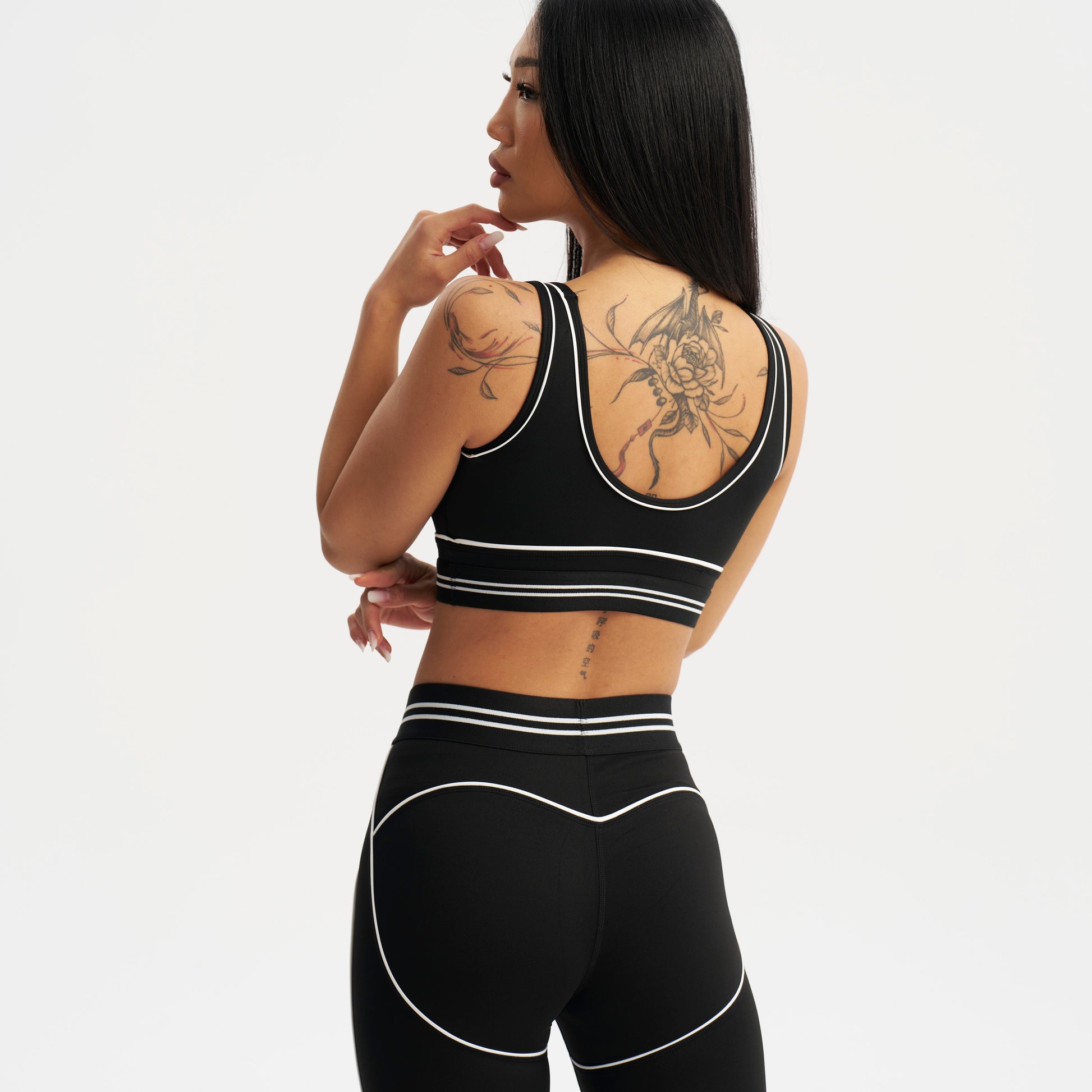 Person wearing a black sports bra and leggings set on a white background